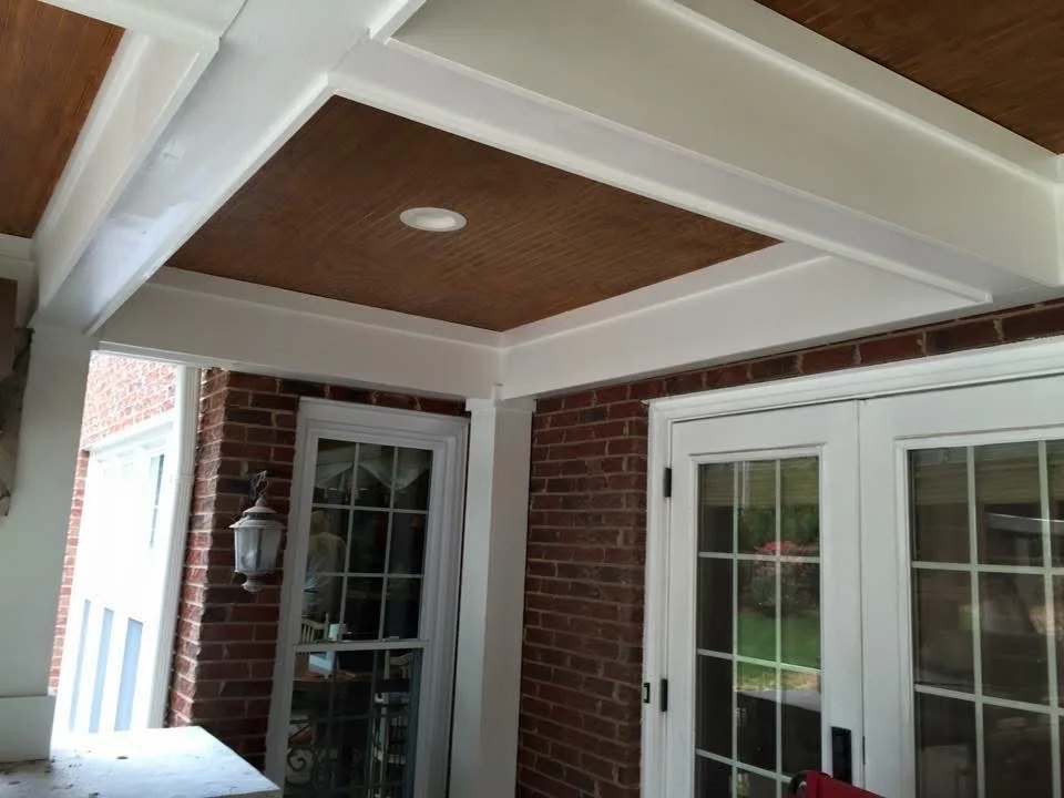 White coffered ceiling with dark wood panels and recessed lighting in covered entry