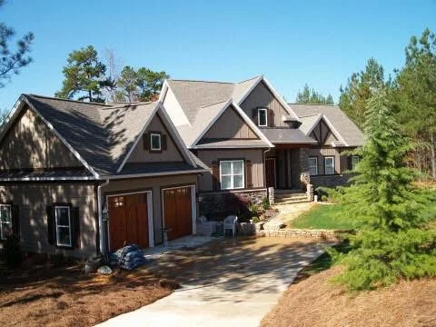 Dark siding home with composite roof, multiple gables, and attached two-car garage