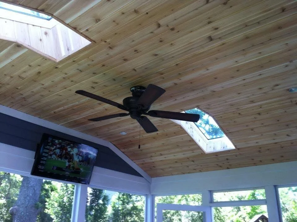 Vaulted wood ceiling with skylight, exposed beams, and black ceiling fan in sunroom
