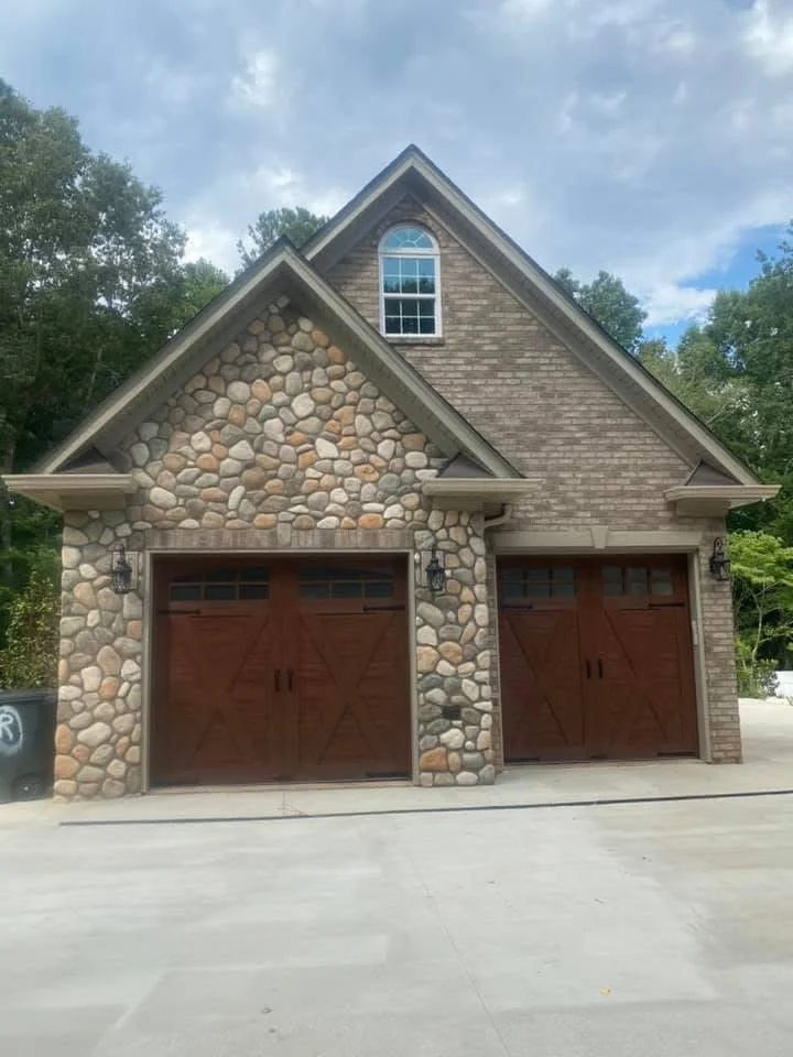 Two-car garage with stacked stone veneer gable and brick siding, dark brown garage doors