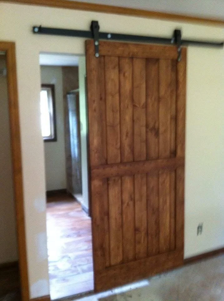 Wooden barn door with vertical planks on black steel sliding track hardware