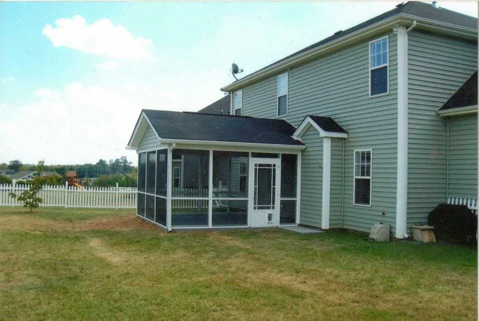 Screened porch addition with white frame, dark shingles, and full screening on residential home
