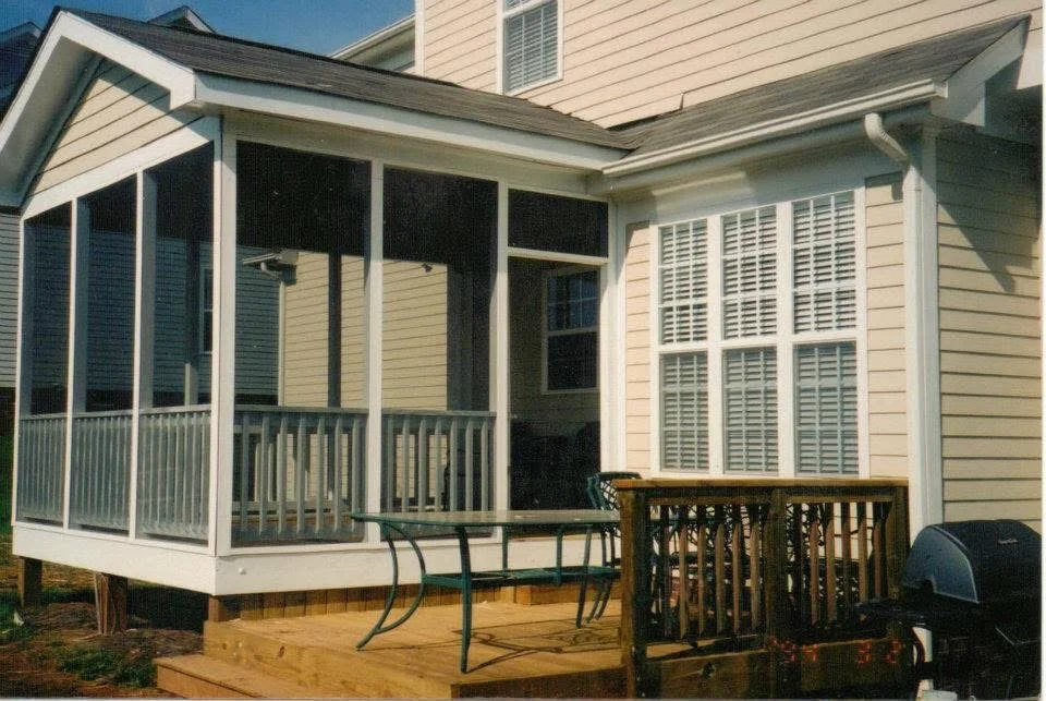 White screened porch with black mesh screens, aluminum railings, and composite deck attached to home