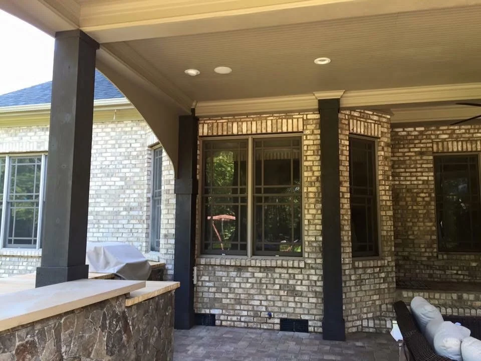 Brick patio with dark wood pergola, recessed lighting, and lattice railings