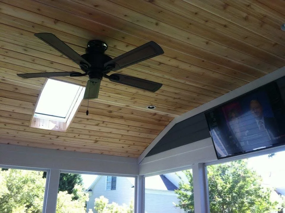Vaulted wood ceiling with skylight, black ceiling fan, and large windows
