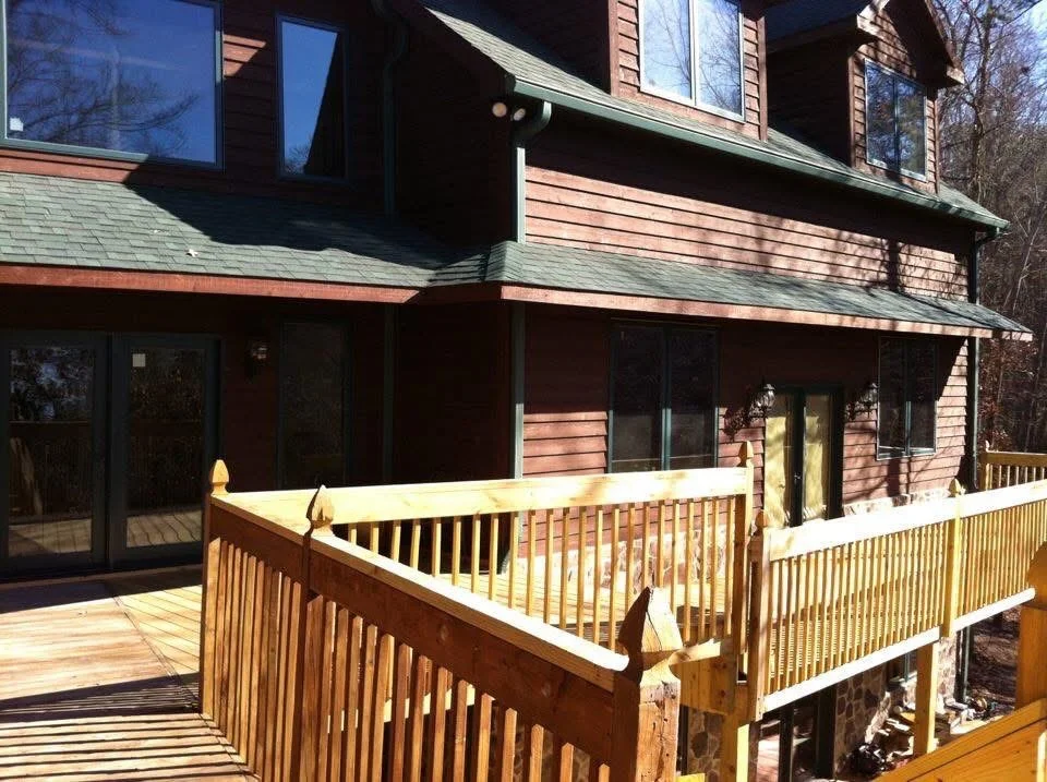 Two-level cedar deck with vertical railings and multiple tiers attached to residential home