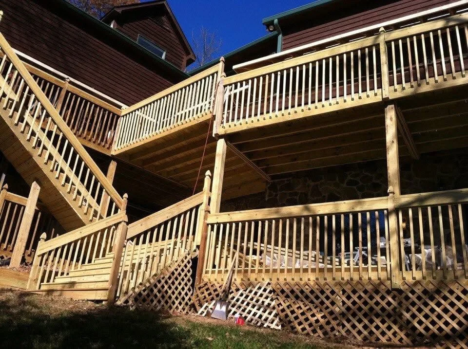 Multi-level pressure-treated wood deck with spindle railings, stairs, and lattice skirting