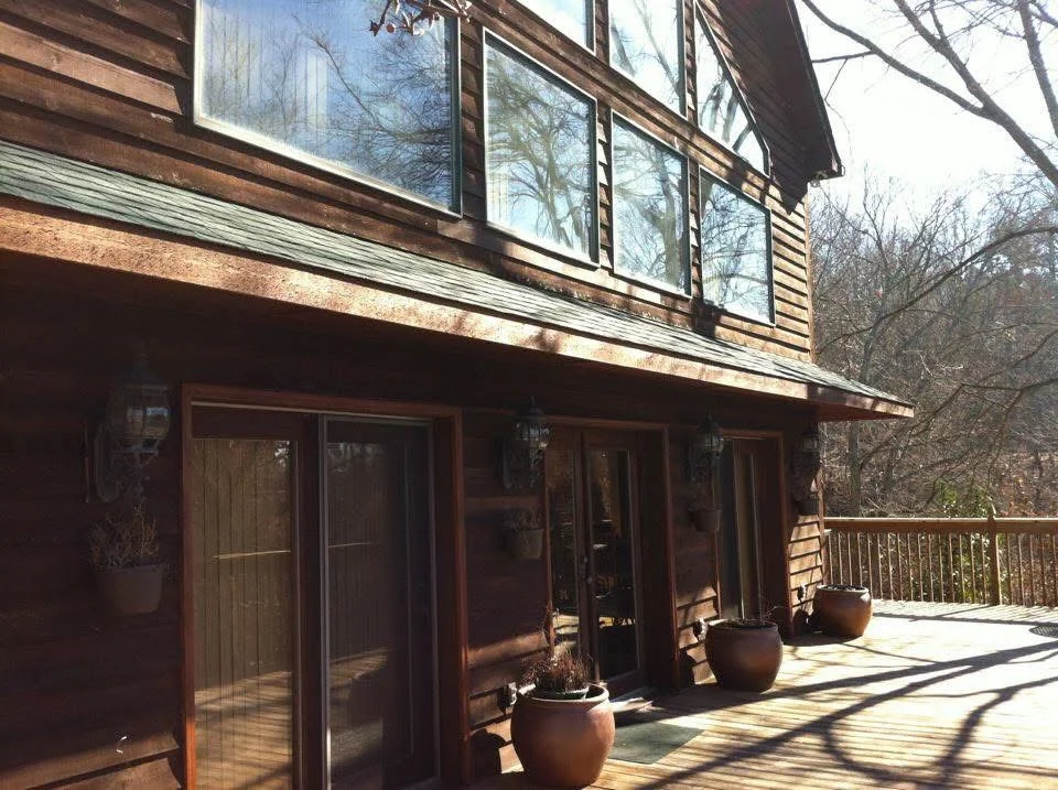 Composite wood deck with glass railing, metal posts, and sliding glass doors on residential home