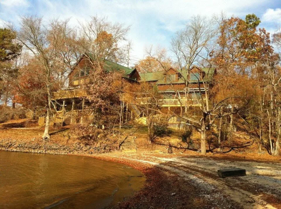 Multi-story brick home with green roof and tiered decks on waterfront lot with mature trees