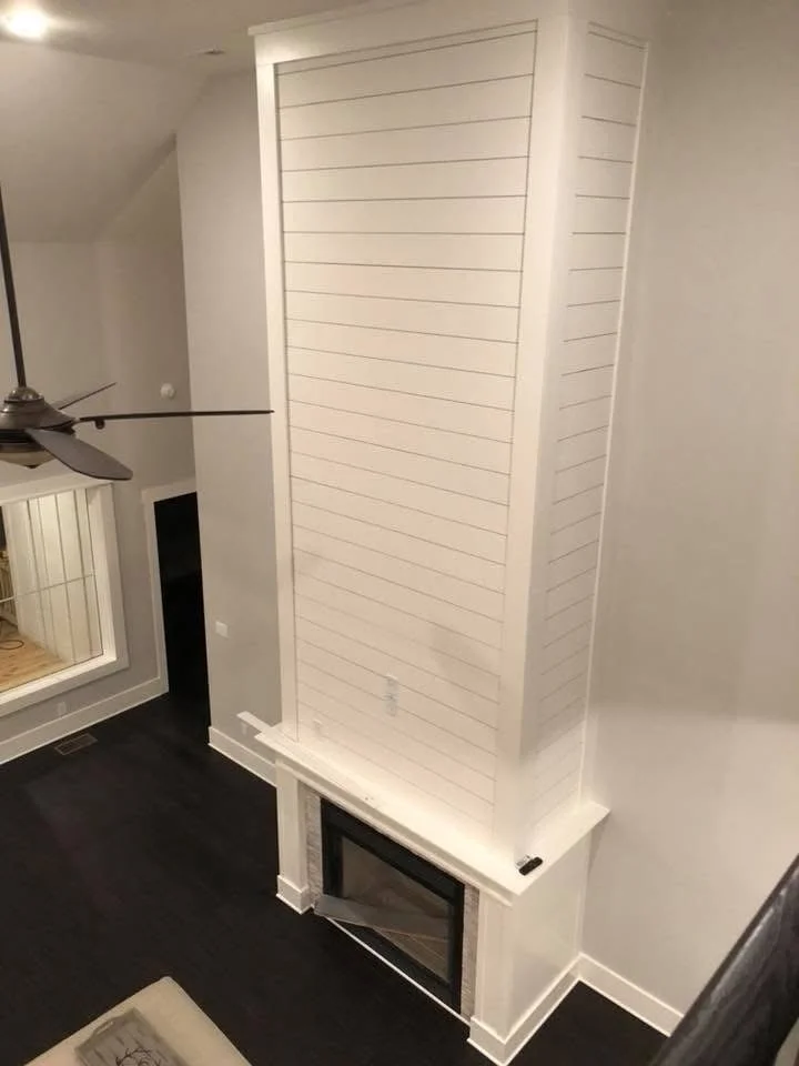 White shiplap fireplace surround with horizontal wood paneling and built-in base platform